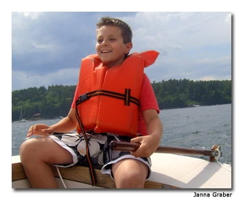 The author’s son sits at the back of the boat with the rudder, calling commands to his crew under the instructor's watchful eyes.